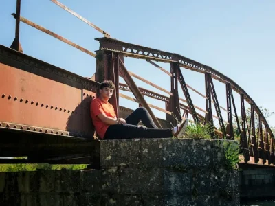 hombre-sentado-puente-pilar-mirando-camara_23-2148187310