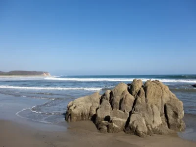 playa-rodeada-mar-rocas-luz-sol-cielo-azul-mexico_181624-17215